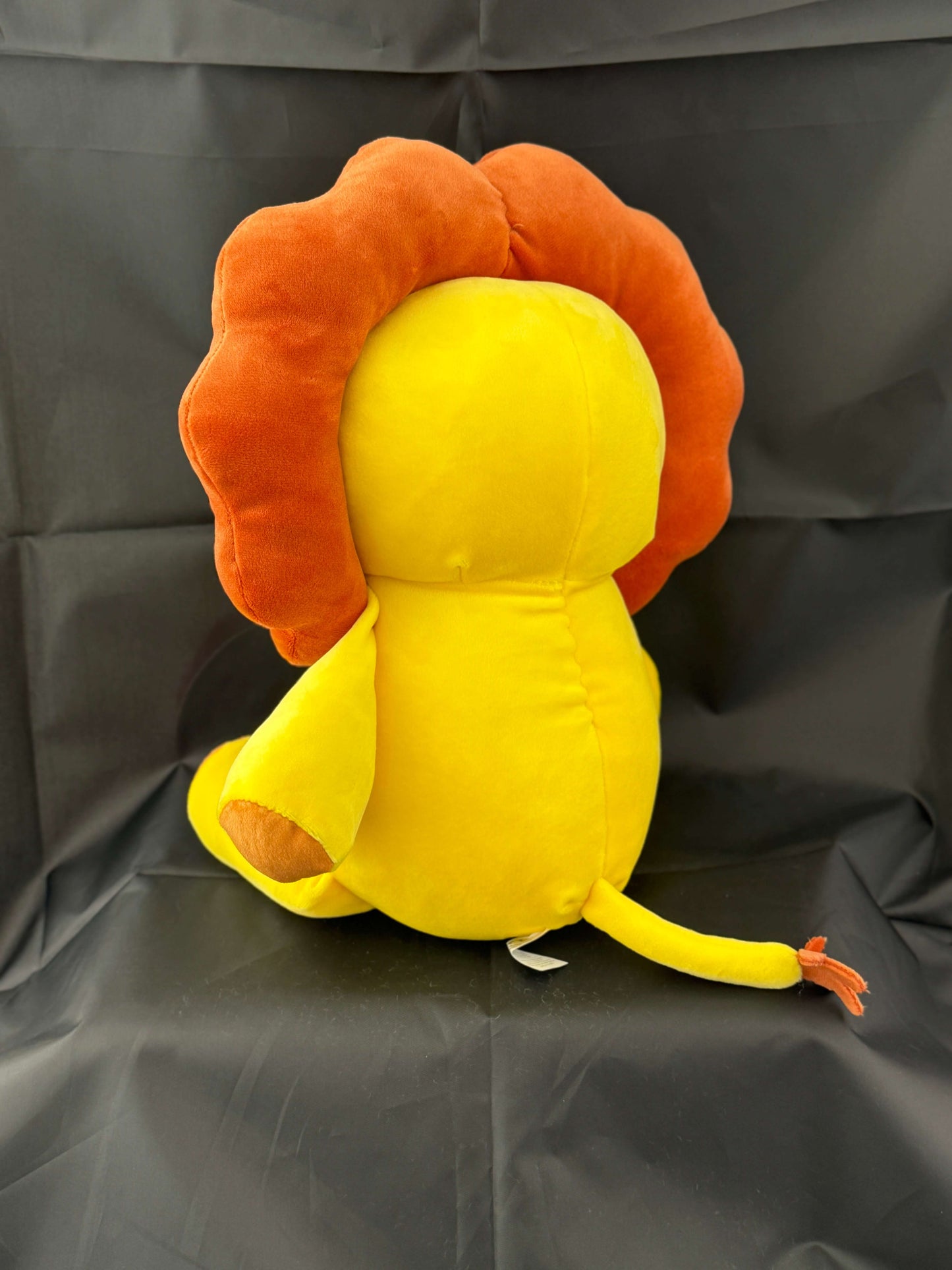 18-inch Leo the Lion plush stuffed animal with vibrant yellow body and detailed brown mane, shown from the back against a black background