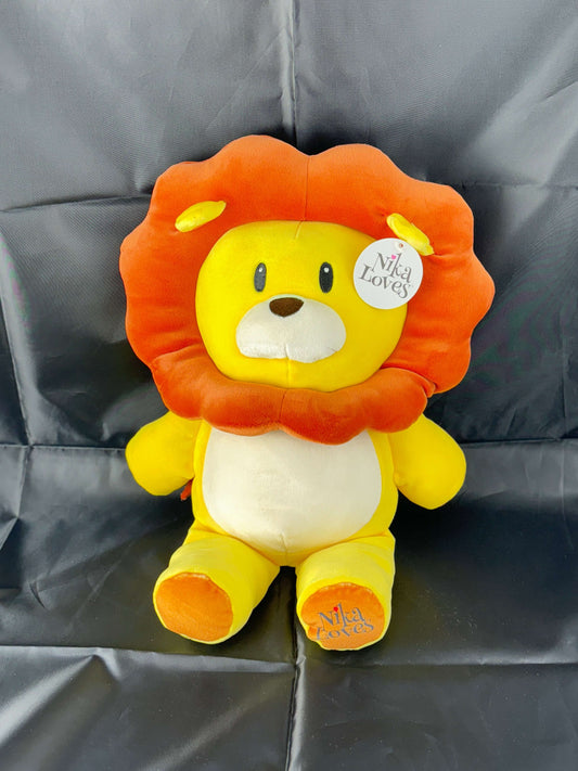Plush lion toy with orange mane and yellow body sitting on a black backdrop.