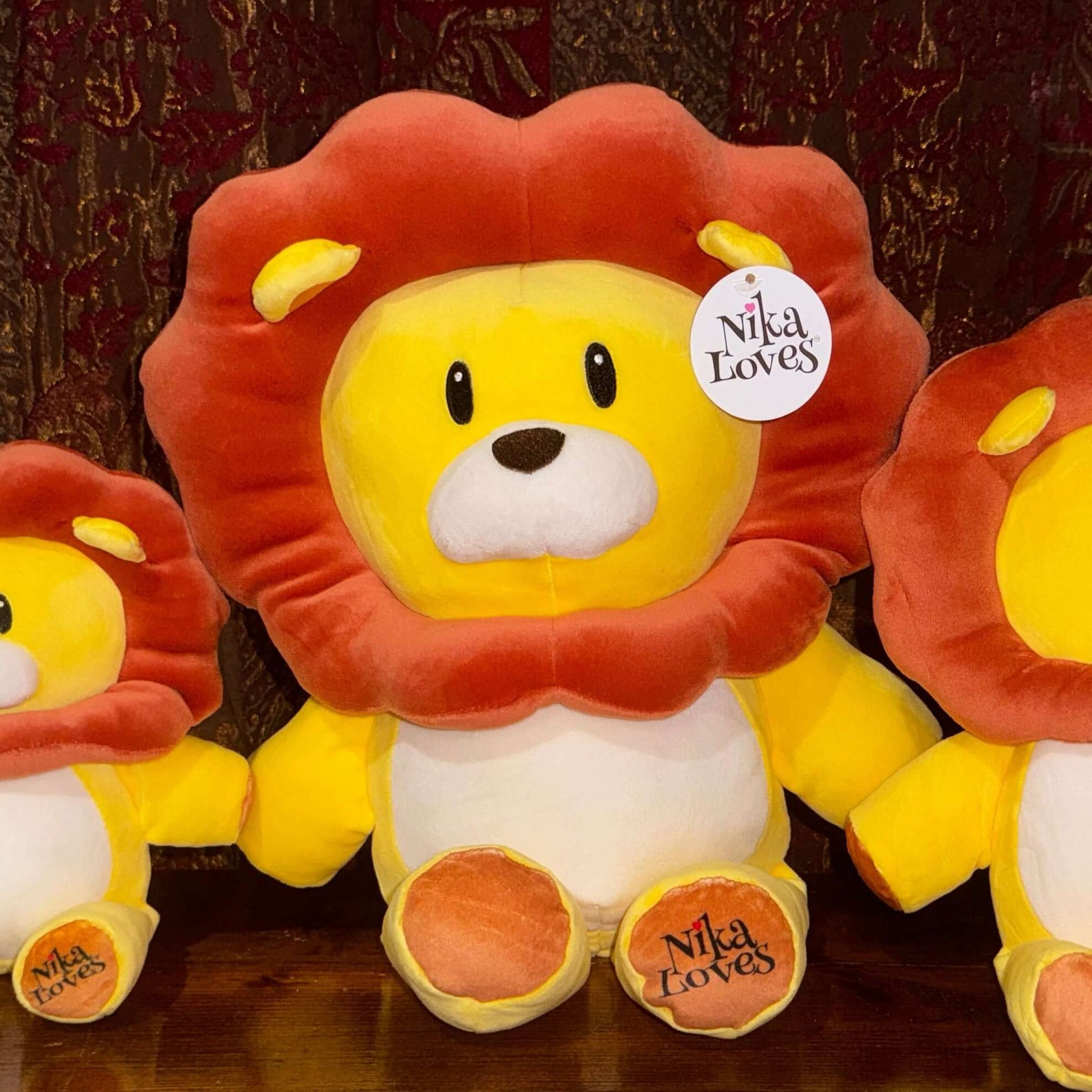 18" Leo the Lion plush stuffed animal with vibrant yellow body, detailed brown mane, and "Nika Loves" tag, perfect for children’s imagination.
